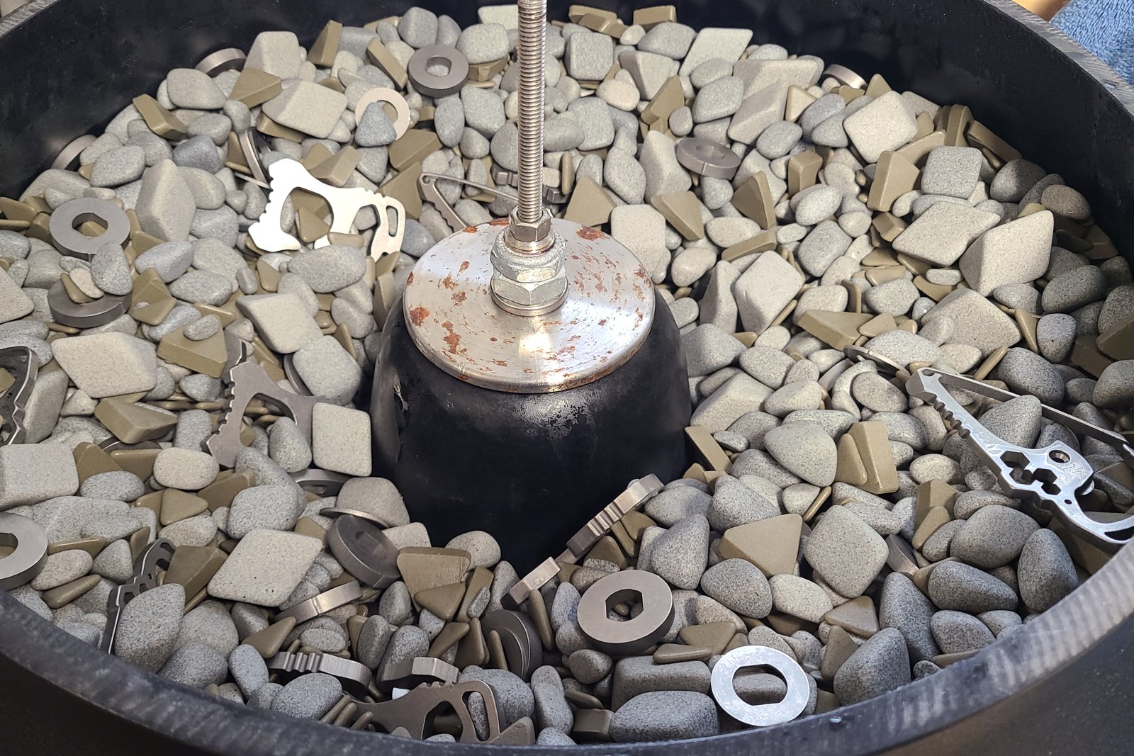 Vibratory bowl with ceramic media and bottle openers and washers being deburred