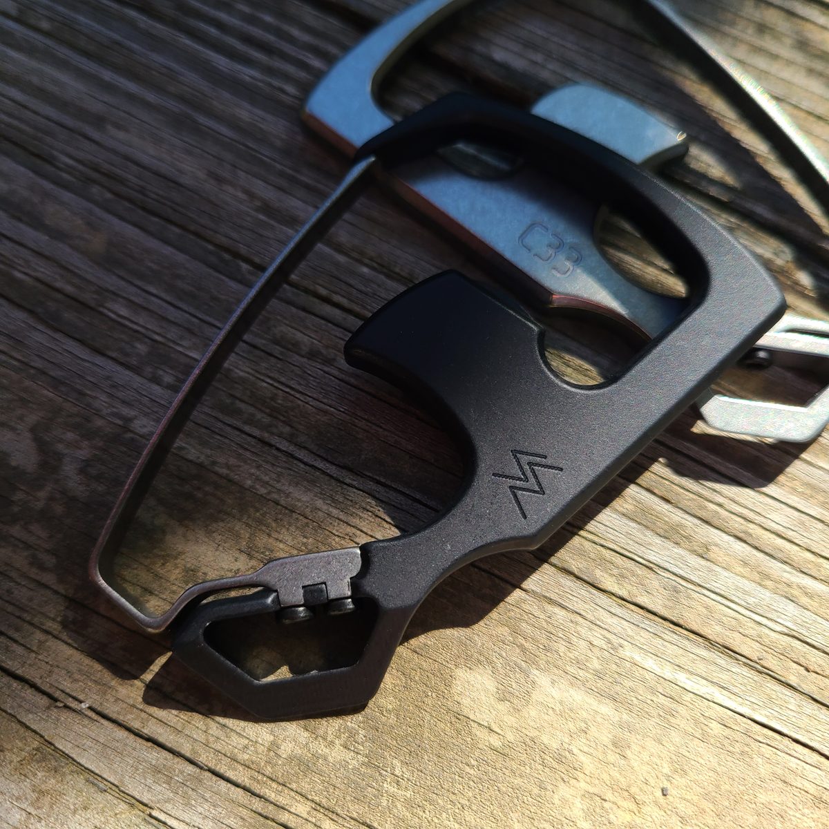 Two C33 carabiners, black and stonewash finish, on wood